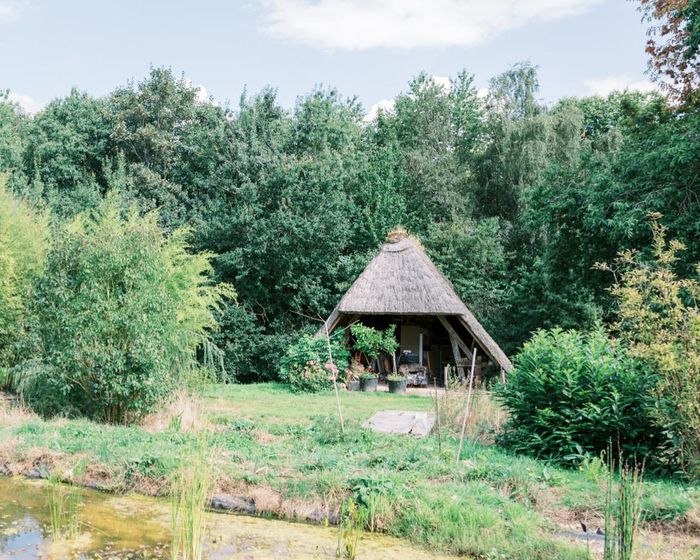 Cabane en chaume près de l'étang, au milieu des arbres